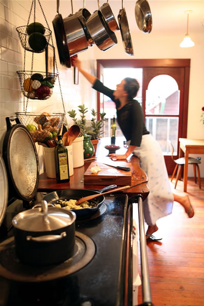 Danielle reaching for a pan in her kitchen while dinner cooks on the stove