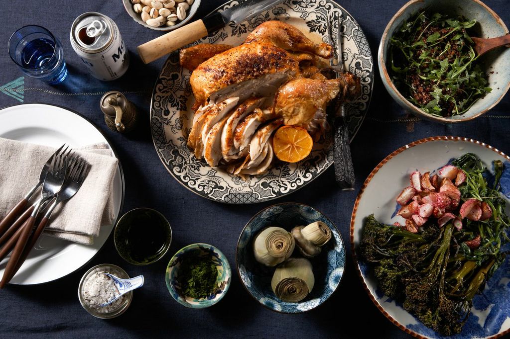 Roast chicken, greens and sides spread across a dark table