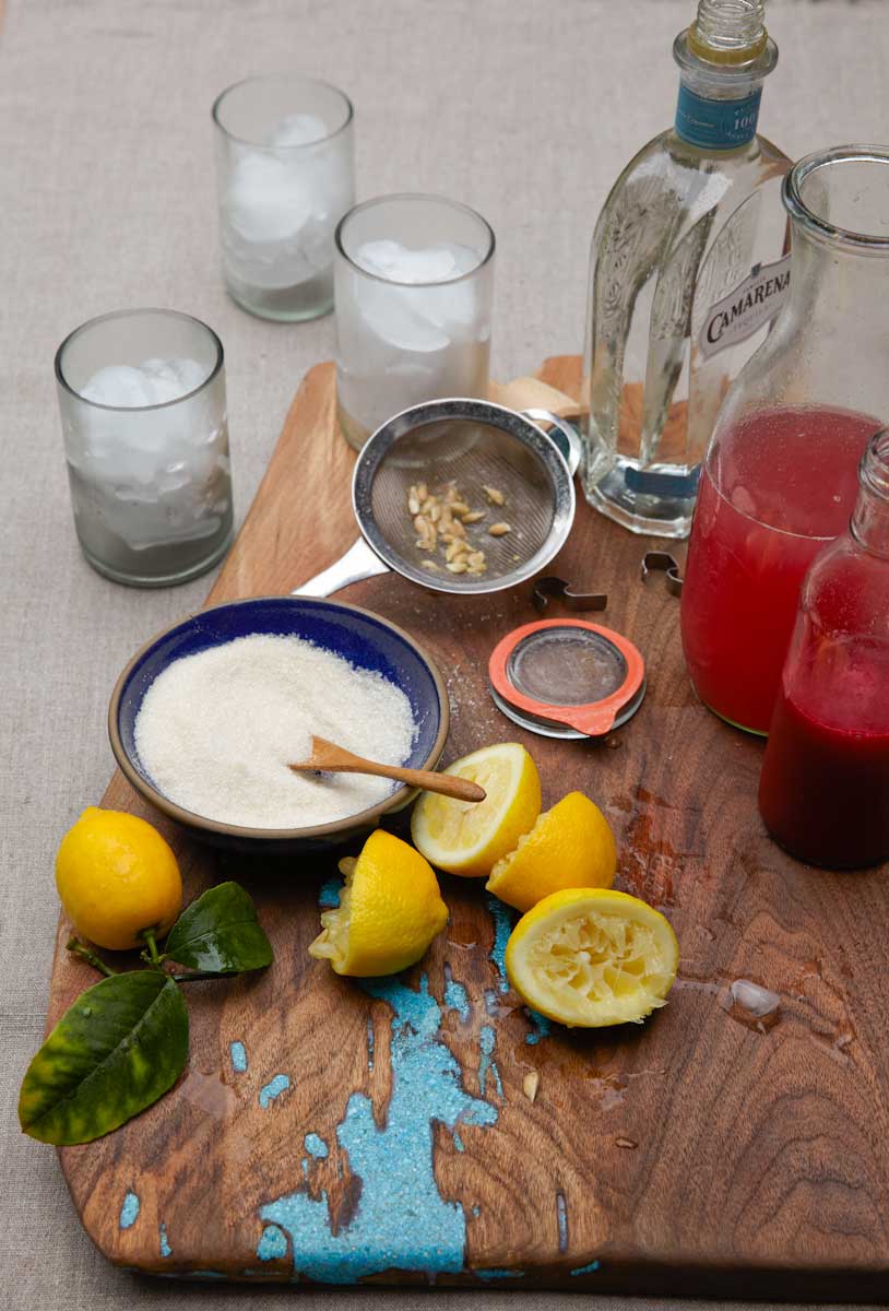 Lemons, pink lemonade and a bowl of cream on a wooden board