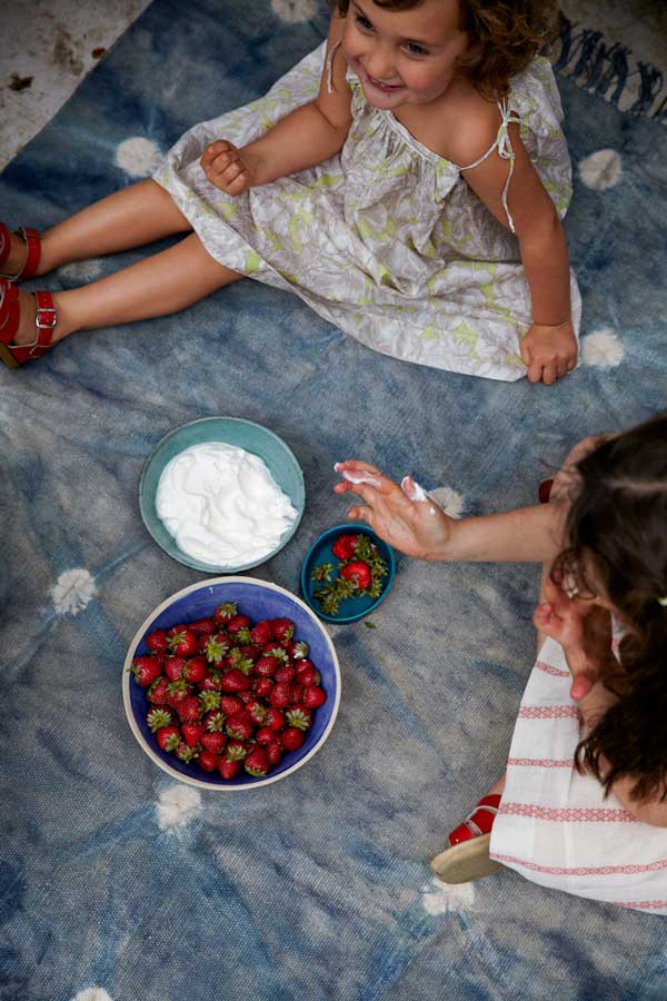 Bowls of strawberries and cream on a blue cloth
