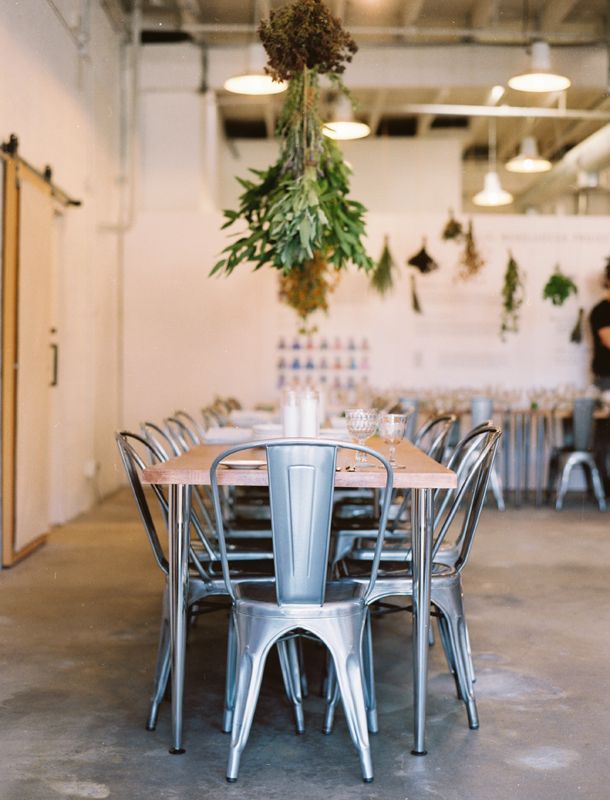 A long dining table beneath hanging herbs
