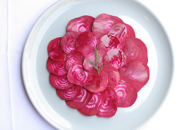 Beet carpaccio fanned across a white plate