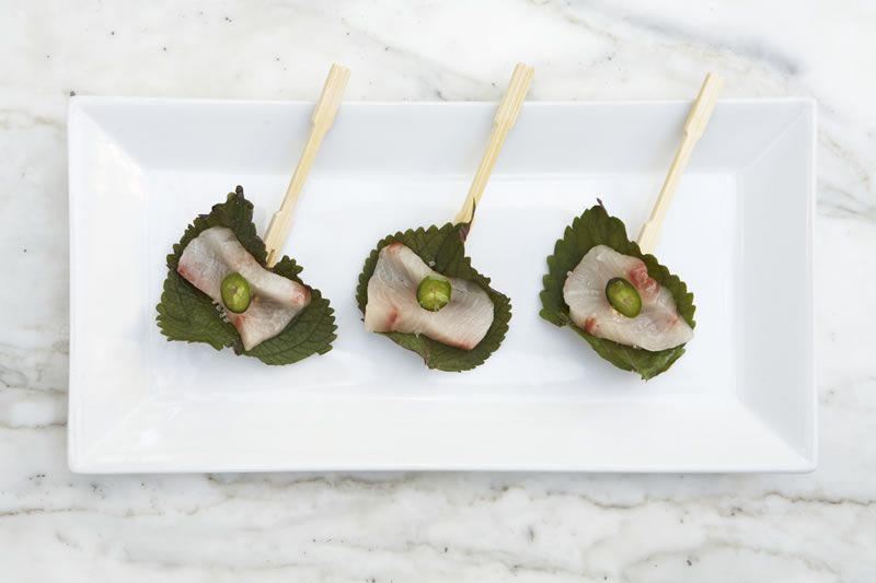 Hamachi wrapped in shiso leaves on bamboo picks